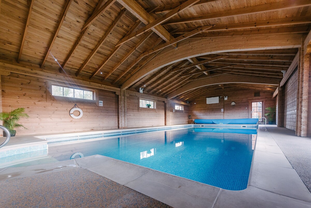 An indoor heated swimming pool in a converted barn with a vaulted roof