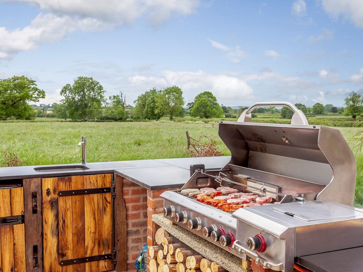An outdoor barbecue and kitchen looking out over open countryside