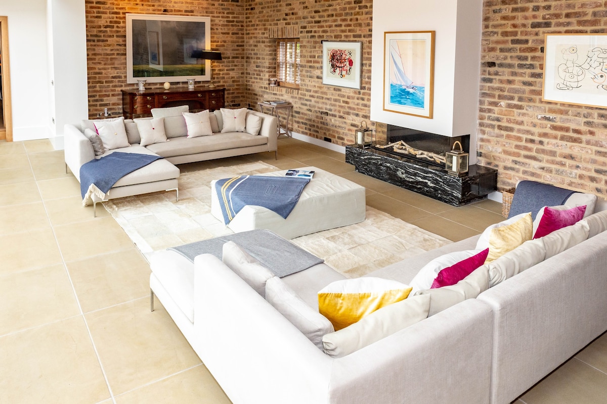 A large open-plan living room with a sectional sofa and brick wall