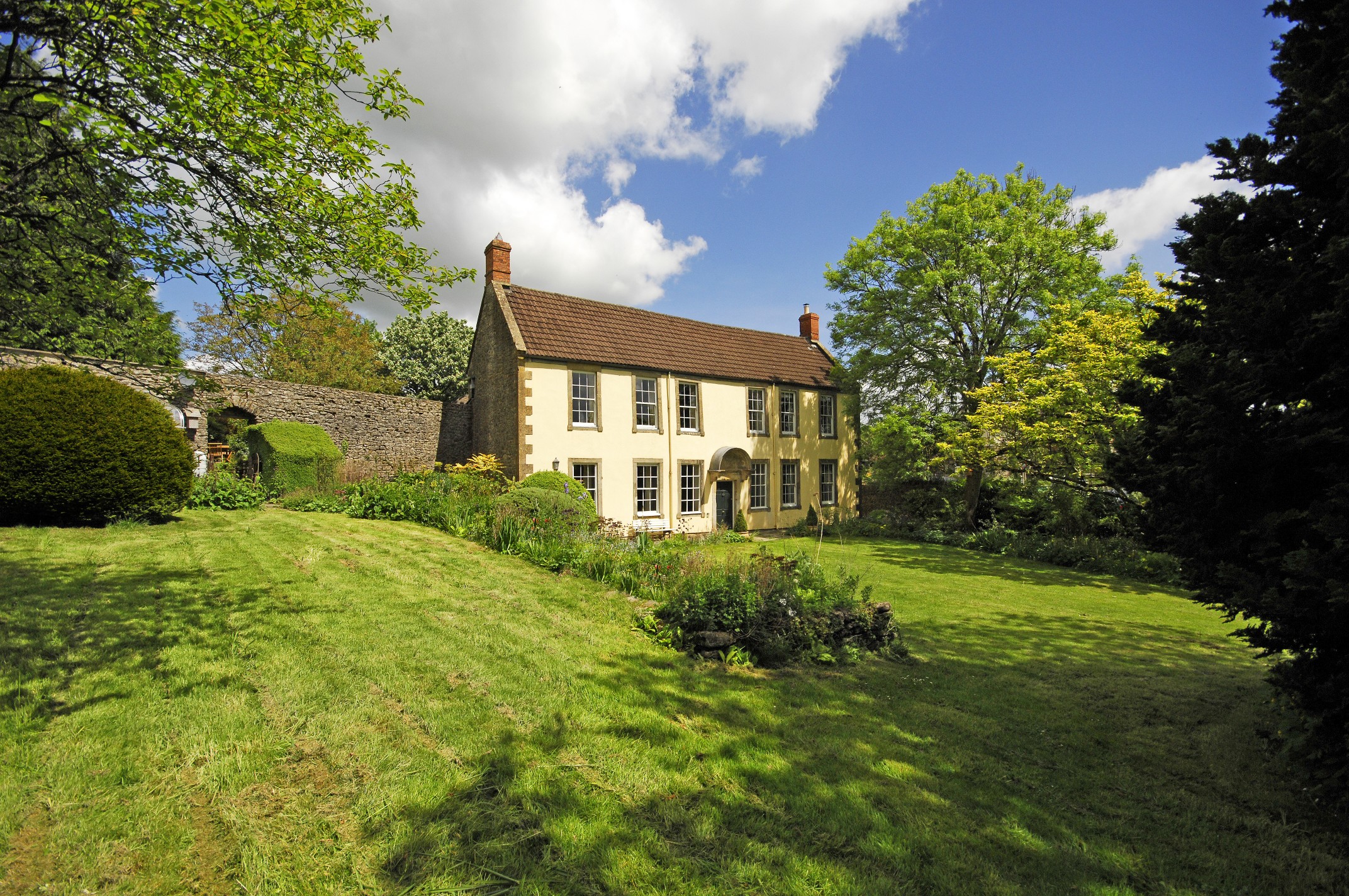 A farmhouse and its lawn on a bright summer day